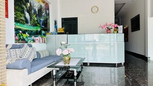 A modern lobby with a sofa, a glass coffee table, and a reception desk. - Ha Thu Motel (Da Nang)