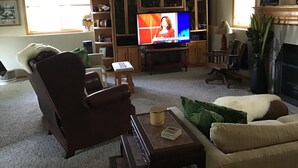 A living room with a television, a brown leather chair, a beige sofa, and a wooden entertainment center. - Location: By Target Center, US Bank Stadium, Target Field & Blaine Sports Ctr! (Blaine)