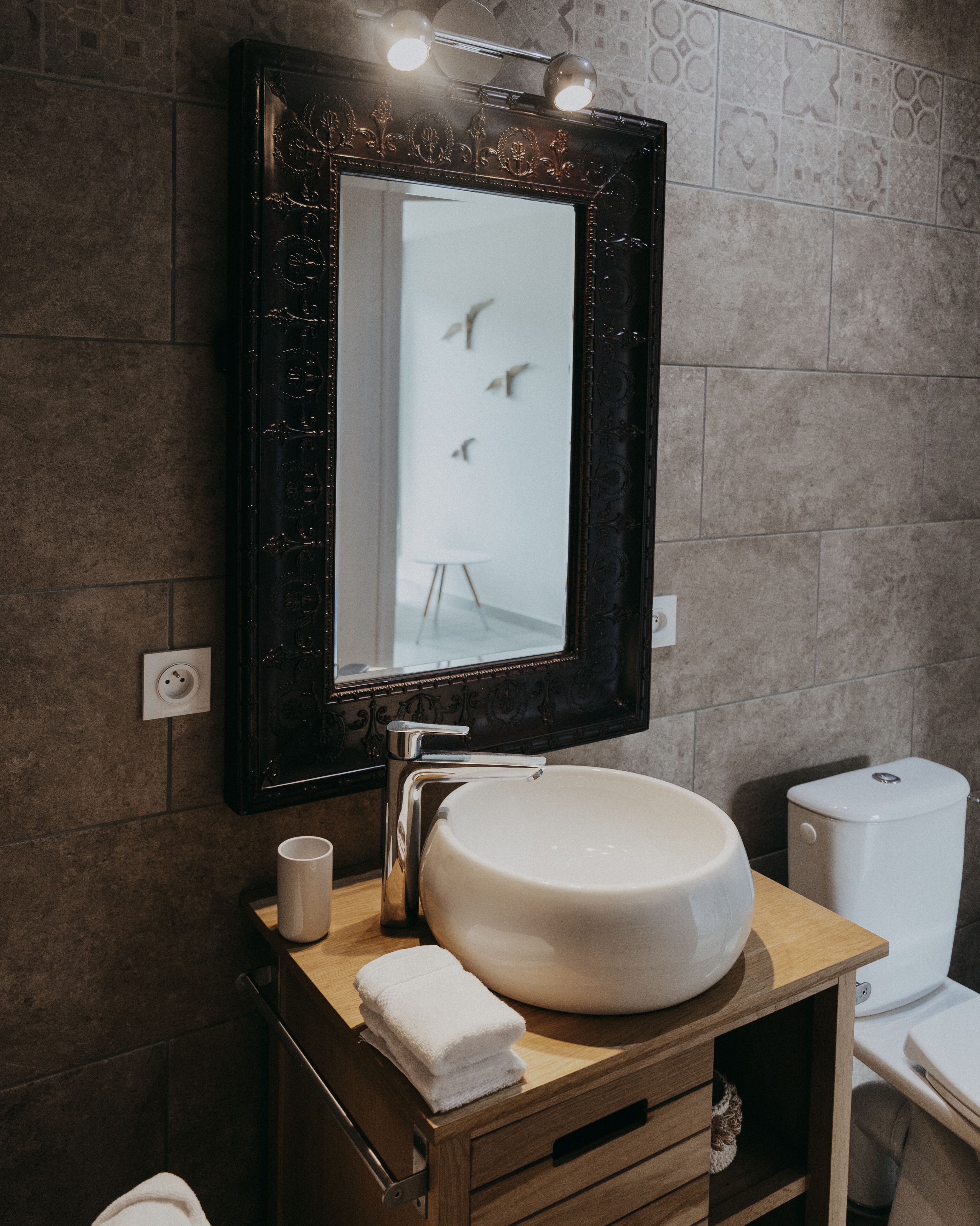 Un baño con un espejo grande, un lavabo redondo, una toalla y un inodoro.