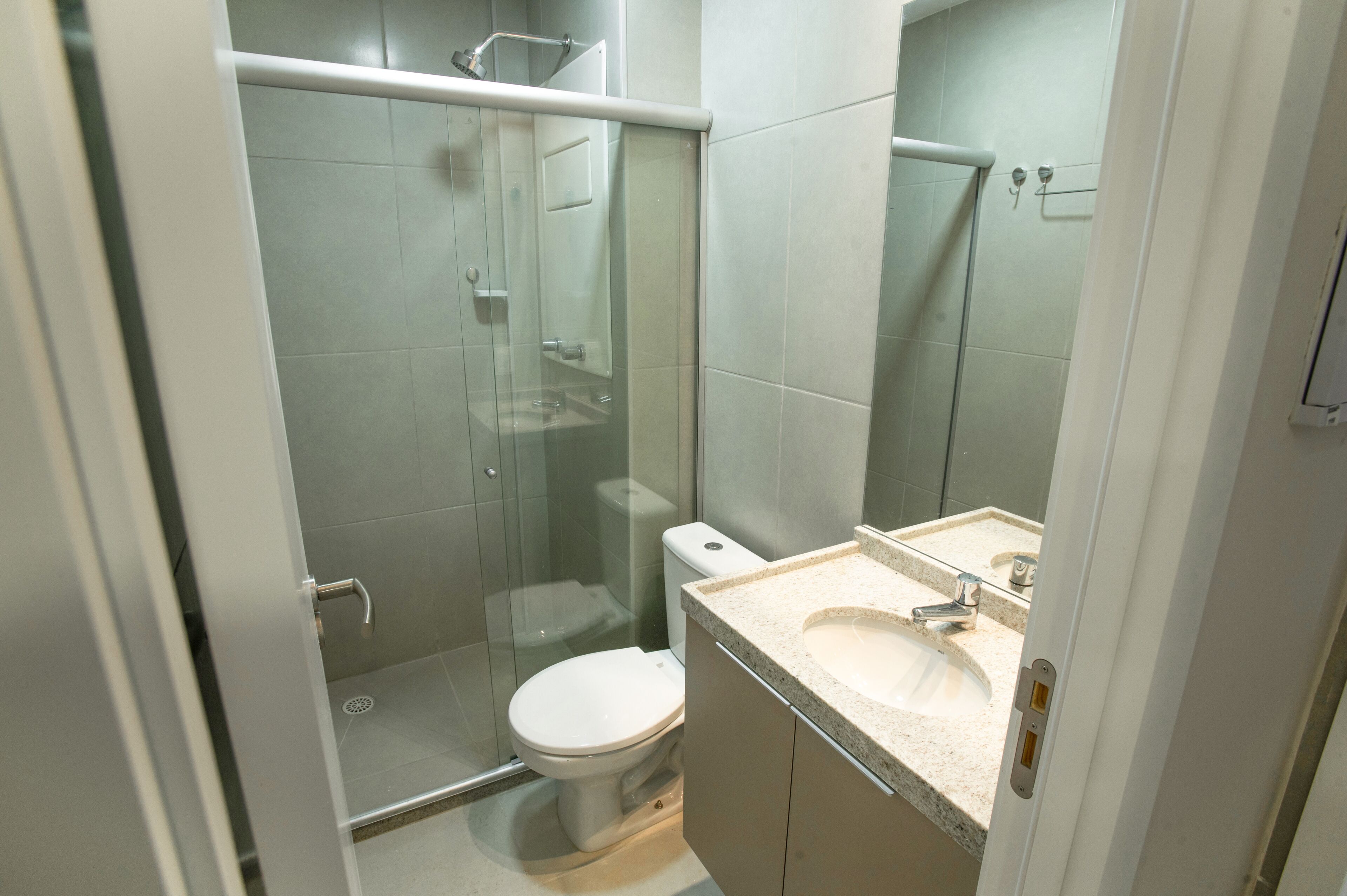 A bathroom with a glass-enclosed shower, a toilet, and a sink with a mirror.