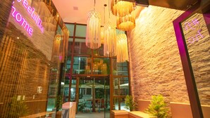 Un interno moderno con lampade a sospensione, una reception e vista sulla zona esterna con posti a sedere.