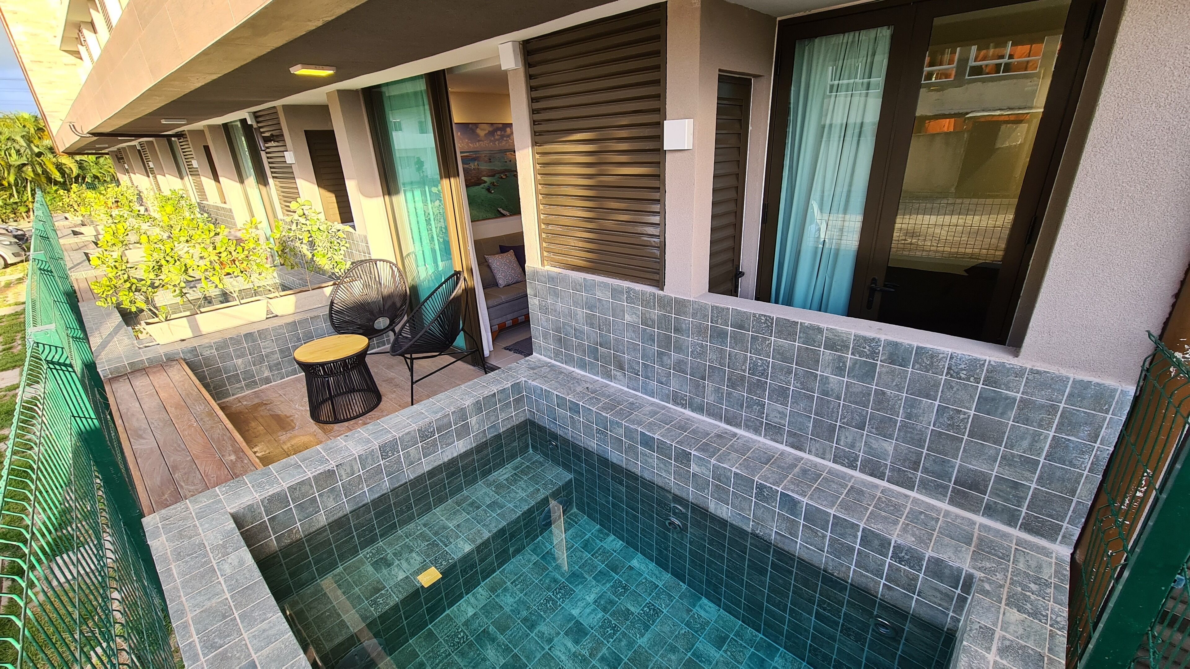 Un espace piscine extérieur moderne, avec des murs carrelés et une terrasse en bois.