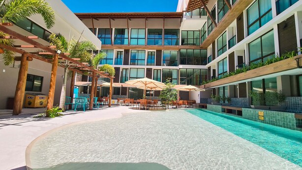 Un hotel moderno con piscina, area relax all'aperto e un edificio a più piani con ampie finestre.