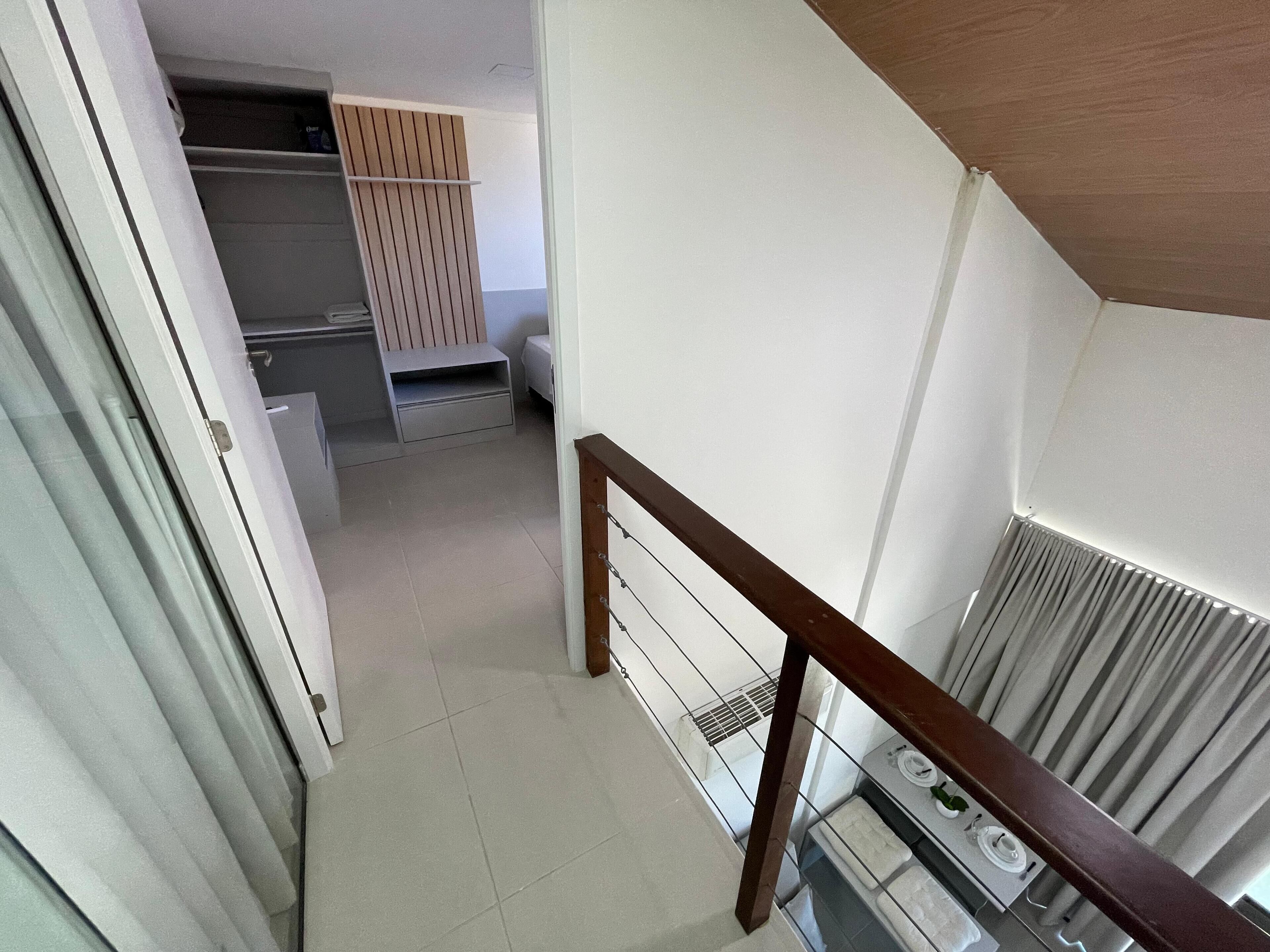 Una escalera conduce a un dormitorio con techo de madera y un radiador.