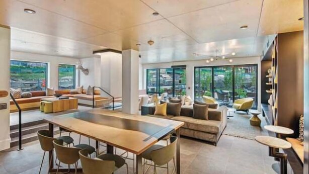Uma sala de estar ampla com uma mesa grande e cadeiras, um conjunto de sofás e uma varanda com área de estar externa.