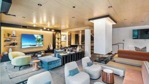 Uma sala de estar moderna com televisão de tela plana, assentos confortáveis e uma grande janela.