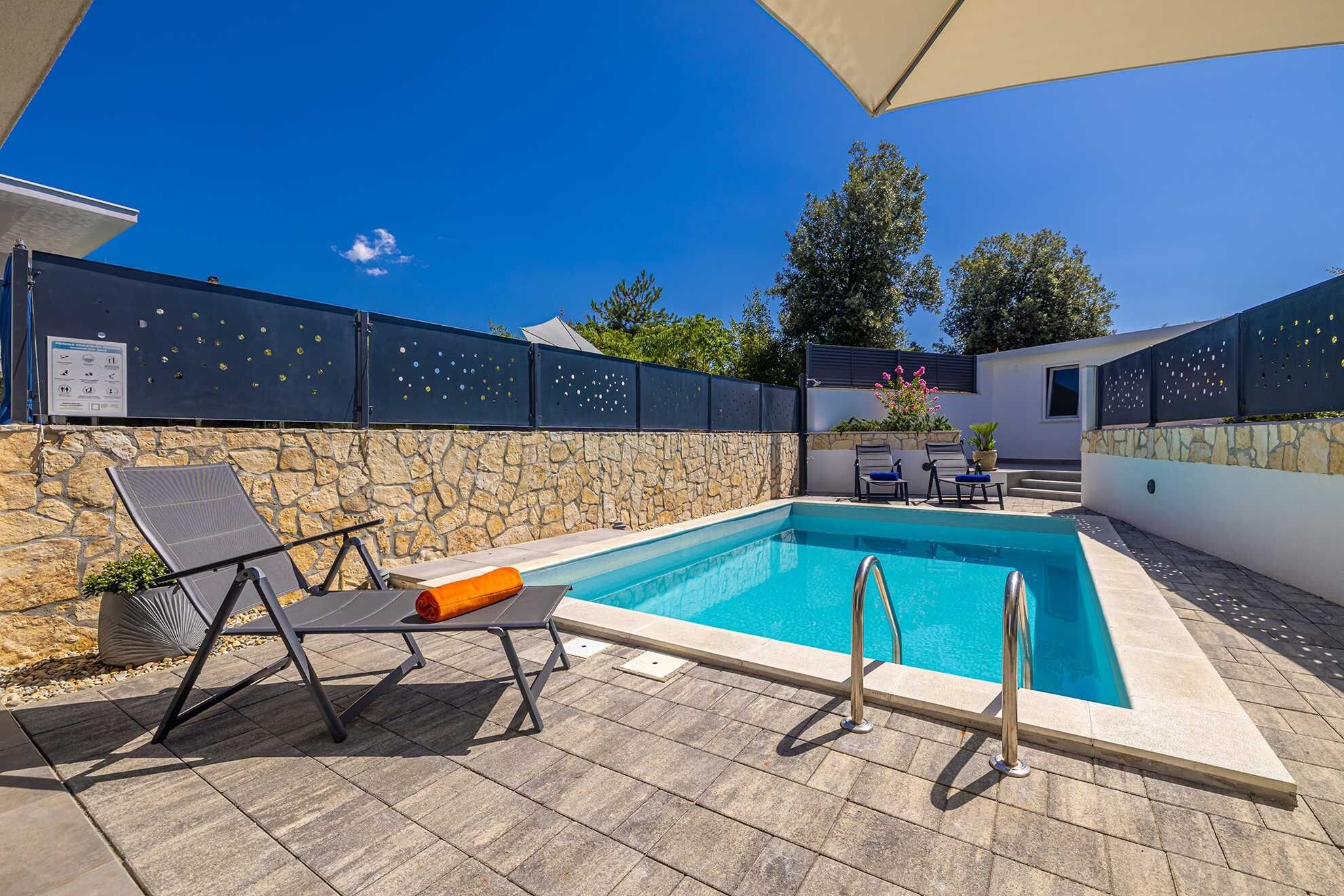 Una piscina con muro in pietra, lettini e una pergola.