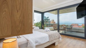 A modern bedroom with a large bed, a wooden wardrobe, and a balcony with outdoor seating. - Villa LARUS with private pool (Malinska)