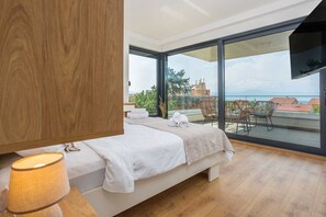 Ein Schlafzimmer mit einem großen Bett, einem Holzschrank, einem Balkon mit Stühlen und Blick auf die Stadt.
