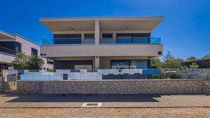 A modern two-story building with a flat roof, large windows, and a stone facade. - Villa LARUS with private pool (Malinska)