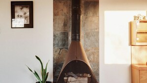 Una sala de estar moderna con chimenea de piedra, un cuadro enmarcado en la pared, una planta en maceta y un tapete de piel de vaca.
