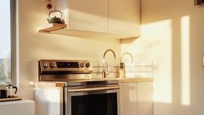 Una cocina moderna con electrodomésticos de acero inoxidable, armarios blancos y encimera de madera.