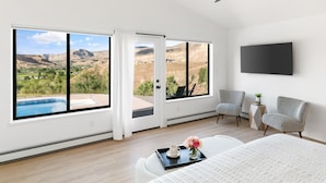A bedroom with a large window, a ceiling fan, a flat-screen TV, and a bed with a tray of items. - The Mesa ViewHouse – Private Pool & Stunning Views – 3BR/3.5BA (Palisade)