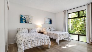 Ein Schlafzimmer mit zwei Betten, einem Nachttisch, einer Lampe und zwei abstrakten Bildern an der Wand.