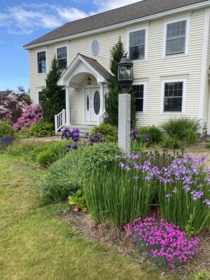 Classic two-story house with a central entrance and a beautifully maintained garden.