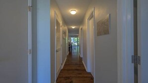 A narrow hallway with wooden flooring and white walls. - Poolside Condo in Surfside Beach (Myrtle Beach)