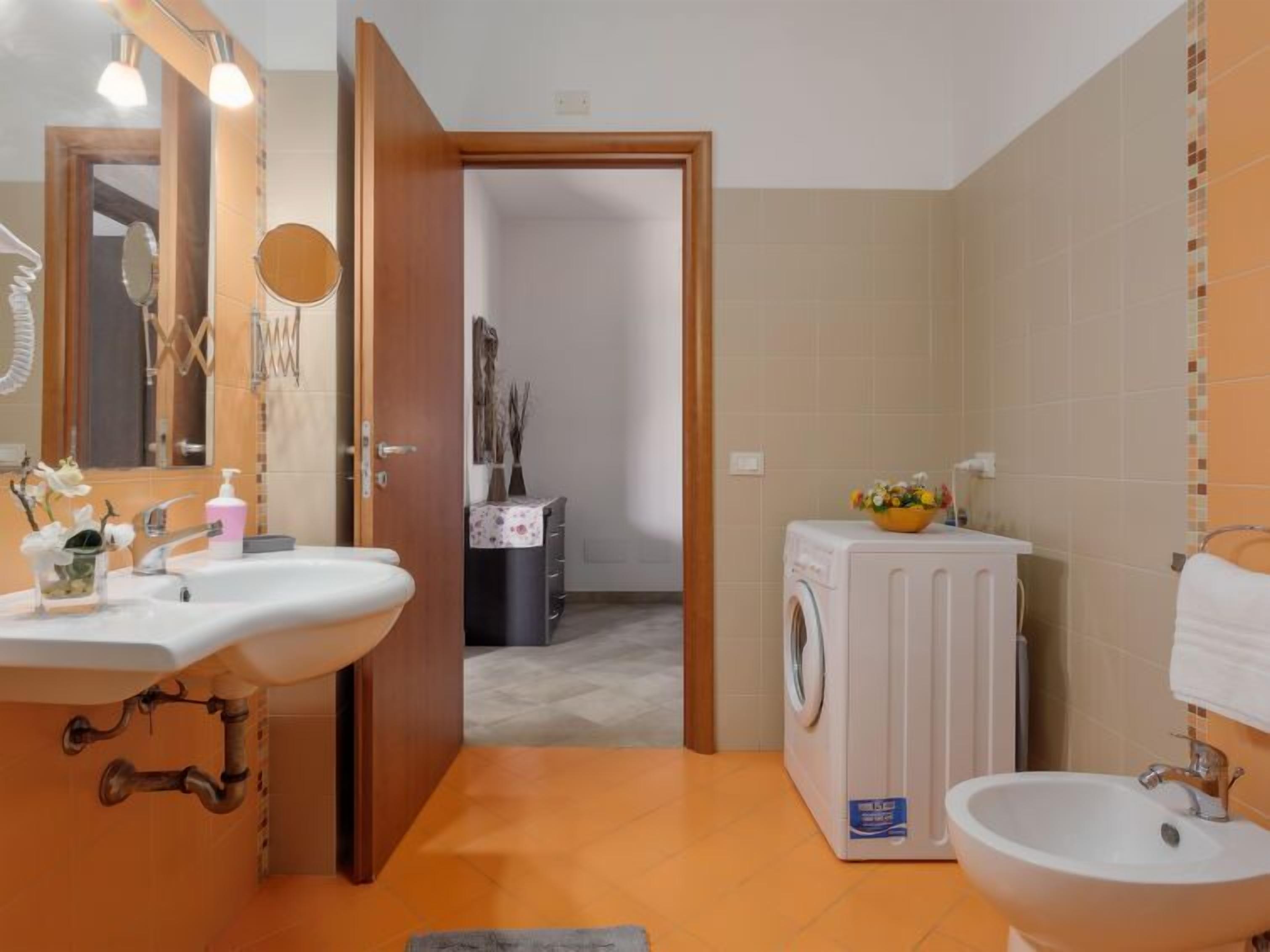A compact bathroom with a sink, mirror, and a washing machine.