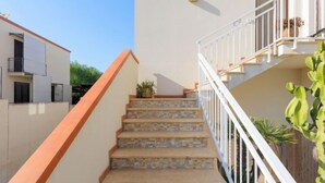 A staircase with stone steps and white railings, leading to a balcony with a potted plant. - Palma Gaia by Interhome (San Vito lo Capo)