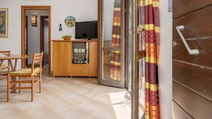 A compact living space with a dining area, kitchenette, and a sliding glass door leading to an outdoor area. - Palma Gaia by Interhome (San Vito lo Capo)