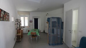 Un vaste espace de vie comprenant une table à manger, une chaise bleue et un espace abrité.