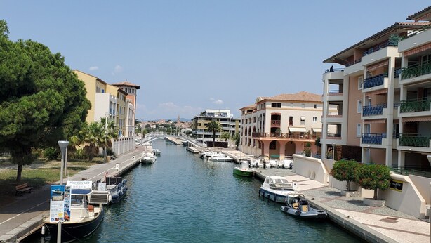 A canal lined with boats, a pedestrian path, and buildings with balconies.