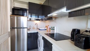 A modern kitchen with stainless steel appliances, a dishwasher, a washing machine, and a coffee maker.
