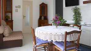 Un comedor con una mesa redonda, sillas, un televisor y un armario.