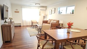Amplia sala de estar con una mesa de comedor de madera, sillas acolchadas, un sofá y una mesa de centro.