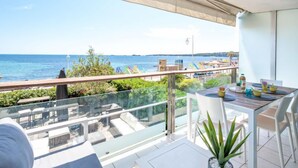 Un balcón con vista al mar, una mesa con sillas y una planta en maceta.