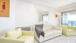 Una sala de estar moderna con un sofá blanco, un sillón más pequeño y un ventanal con vistas.