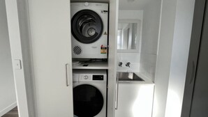 A laundry room with a washing machine, dryer, and a sink. - Modern Kings Beach: Walk to Beach (CALOUNDRA)