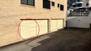 A building with a brick facade, multiple garage doors, and a no parking sign. - Modern Kings Beach: Walk to Beach (CALOUNDRA)