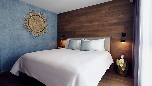 Un dormitorio con una cama grande, cabecero de madera, dos lámparas de noche y un adorno en la pared.