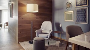 Ein modernes Wohnzimmer mit einer Wand in Holzoptik, einer Stehlampe, einem runden Hocker und einem Esstisch mit einer weißen Tasse.