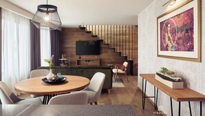Ein modernes Wohnzimmer mit einem runden Holzes Esstisch, einer Couch und einem an der Wand montierten Fernseher.