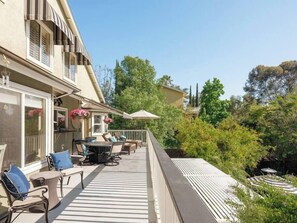 Un balcon agrémenté de mobilier d’extérieur, d’une pergola et d’une végétation luxuriante.