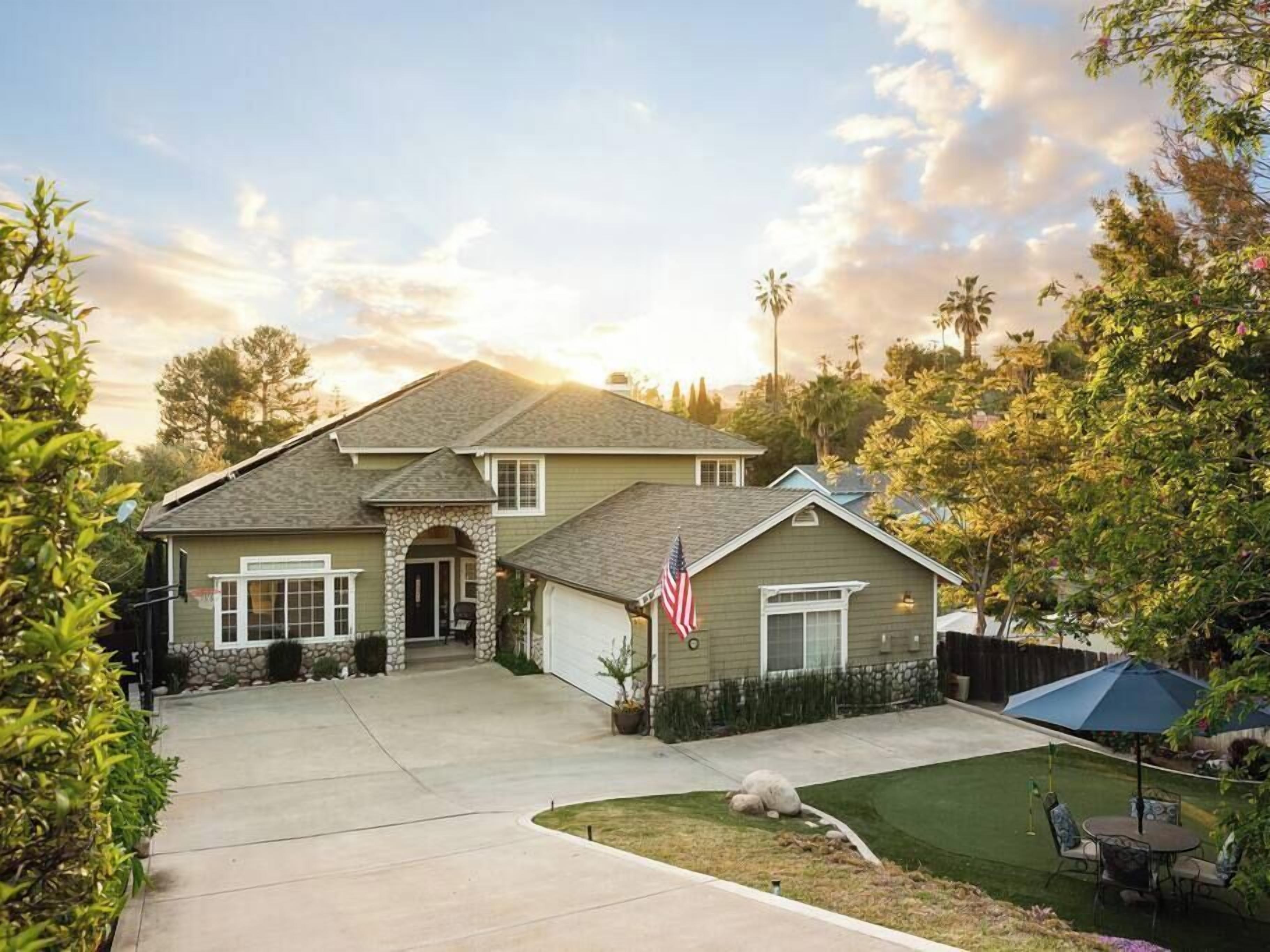 A two-story house with a stone archway entrance, a garage, and a well-maintained lawn.