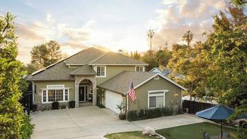 A two-story house with a stone archway entrance, a garage, and a well-maintained lawn.