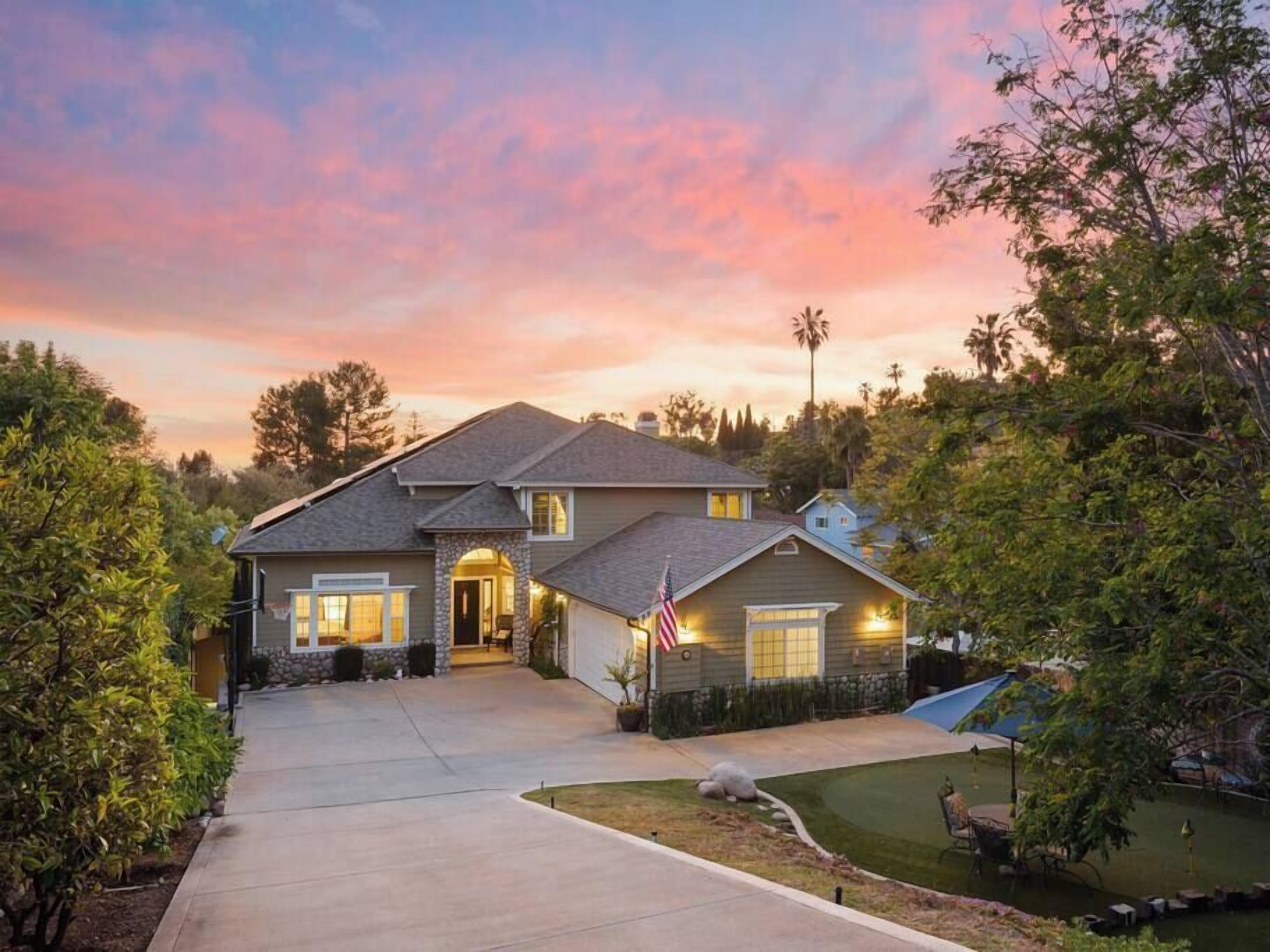 A two-story house with a stone entrance, a driveway, and a well-maintained lawn.