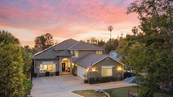 A two-story house with a stone entrance, a driveway, and a well-maintained lawn.