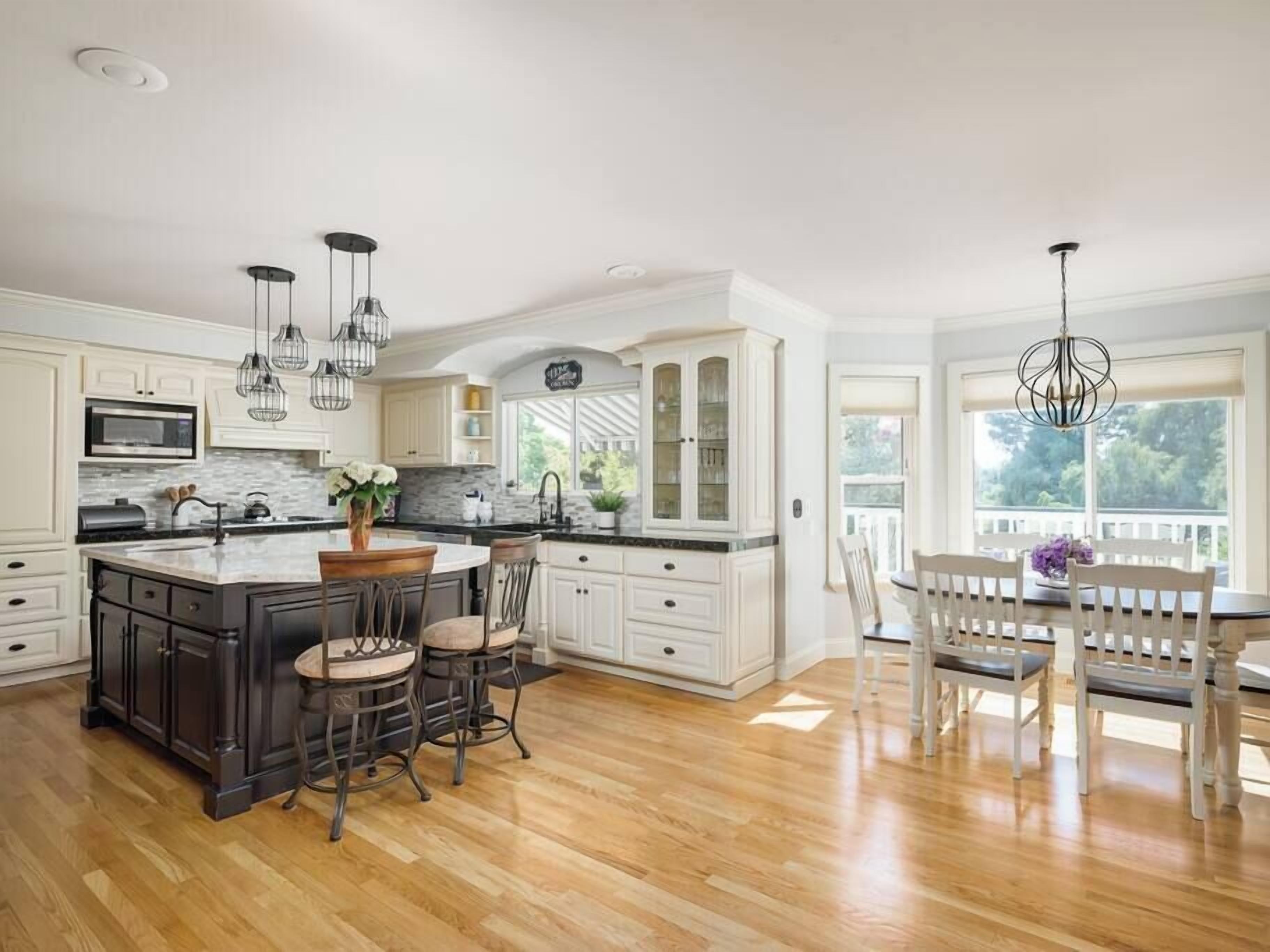 A spacious kitchen with a central island, bar stools, and a dining area with a table and chairs.