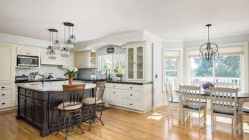 A spacious kitchen with a central island, bar stools, and a dining area with a table and chairs.