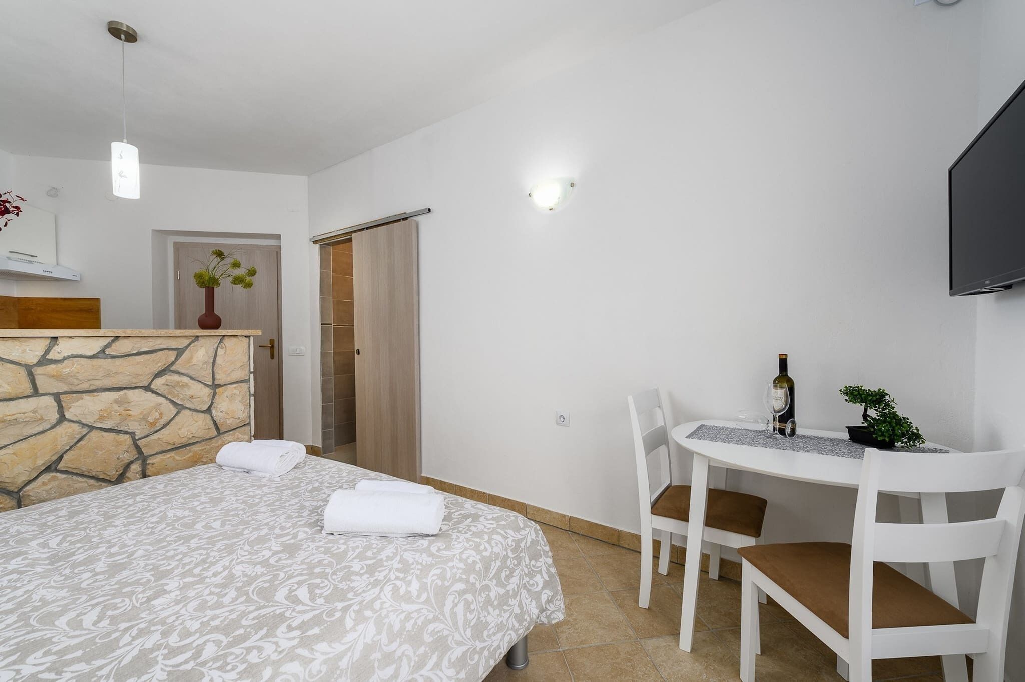 Habitació d'hotel amb un llit, un escriptori amb una cadira, una televisió i una porta que dona a un bany.