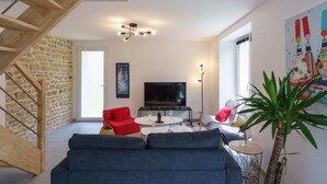 Ein modernes Wohnzimmer mit Treppe, Flachbildfernseher und einer großen Topfpflanze.