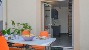 An outdoor dining area with a table and chairs, a bowl of fruit, and a potted plant. - Maison Des Lilas by Interhome (Quiberon)