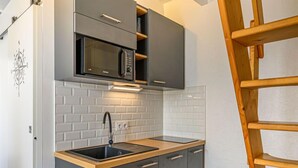 A compact kitchen with a microwave, sink, and wooden countertop. - Maison Des Lilas by Interhome (Quiberon)