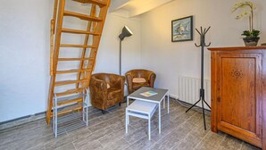 A room with a wooden ladder, two brown leather chairs, a white table, a radiator, a floor lamp, a coat rack, and a wooden cabinet. - Maison Des Lilas by Interhome (Quiberon)