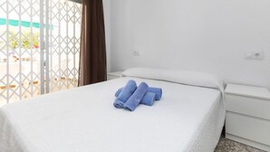 A hotel room with a bed, a white nightstand, and a window with a view of the outside. - Peñismar Garden by Interhome (Peñiscola)