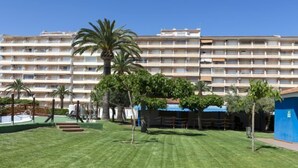 A hotel courtyard with a well-maintained lawn, palm trees, and a pool area. - Peñismar Garden by Interhome (Peñiscola)