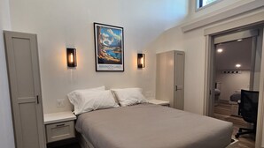 A modern bedroom with a large bed, a nightstand, a wardrobe, and a view of the room's interior through an open door. - Mammoth Lakes Condo-Newly remodeled-Sleeps up to 8 (Mammoth Lakes)